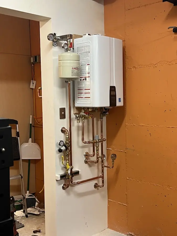 Plumbing technician inspecting water heater connections in Media